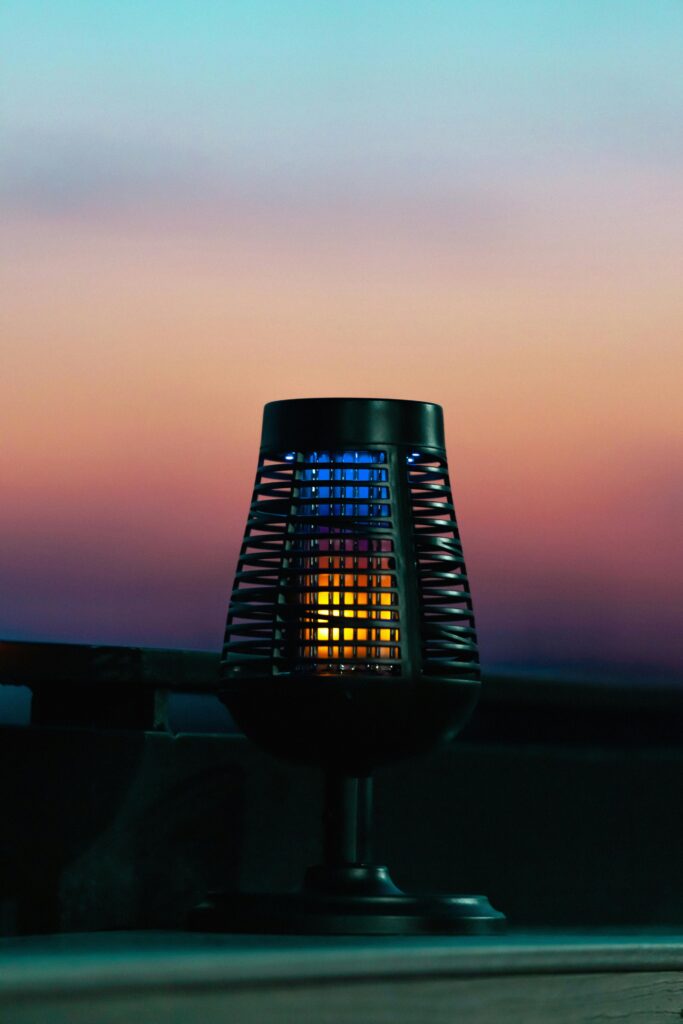 Electric bug zapper lamp illuminated against a beautiful twilight sky, providing effective pest control.